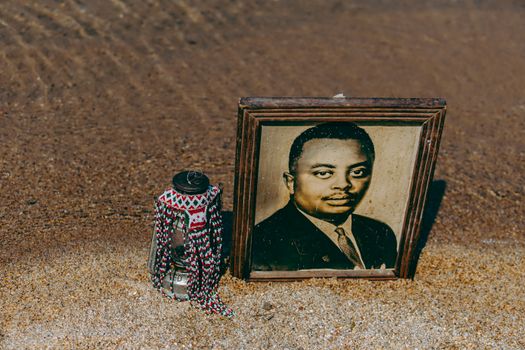 Framed portrait and decorative jar on sandy beach in Bujumbura Mairie, Burundi.