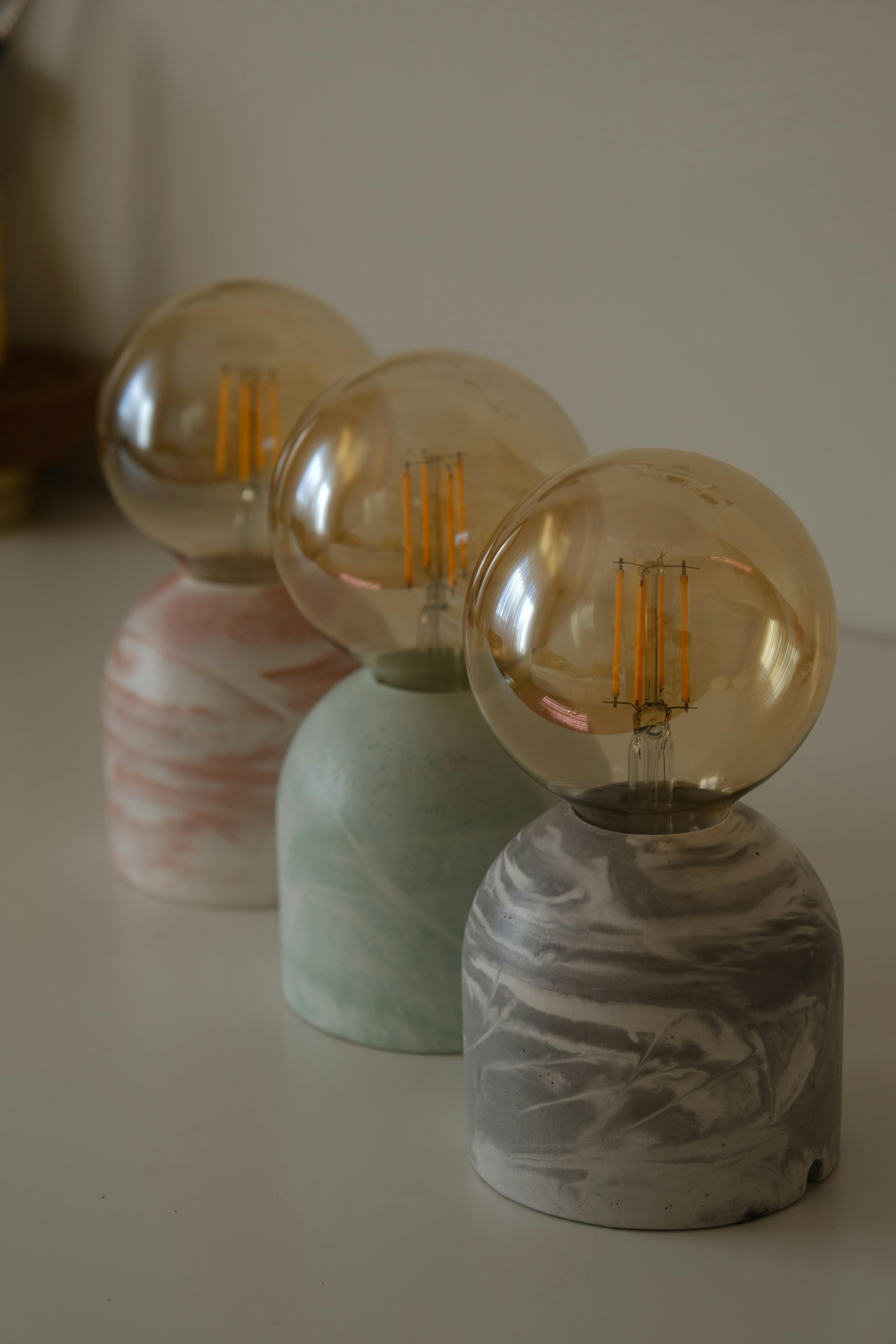Three decorative LED bulbs with marble bases showcased indoors, ideal for modern interiors.
