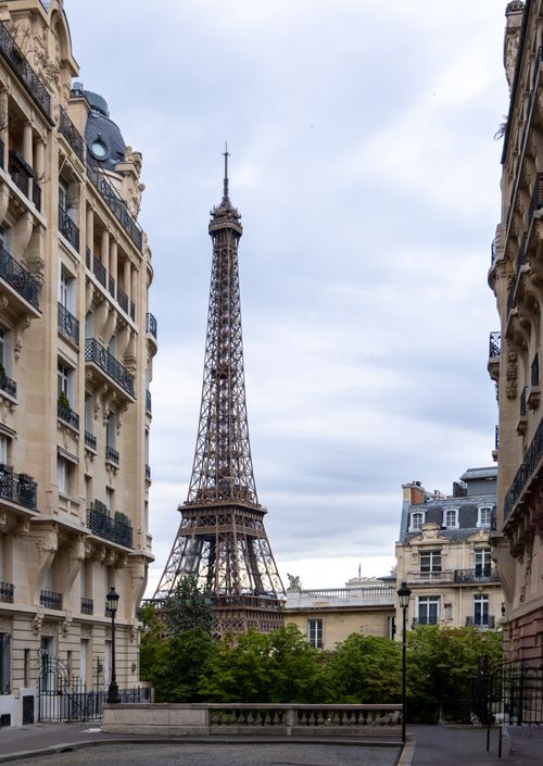 Free Elegant view of the Eiffel Tower framed by historic Parisian architecture on a cloudy day. Stock Photo