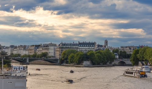 Free Explore the Seine River with iconic Parisian architecture and peaceful riverboats under a cloudy summer sky. Stock Photo