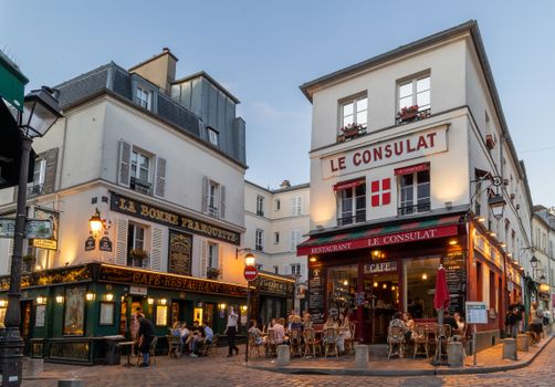 Scenic view of bustling outdoor cafés in Montmartre, Paris, capturing Parisian nightlife charm.
