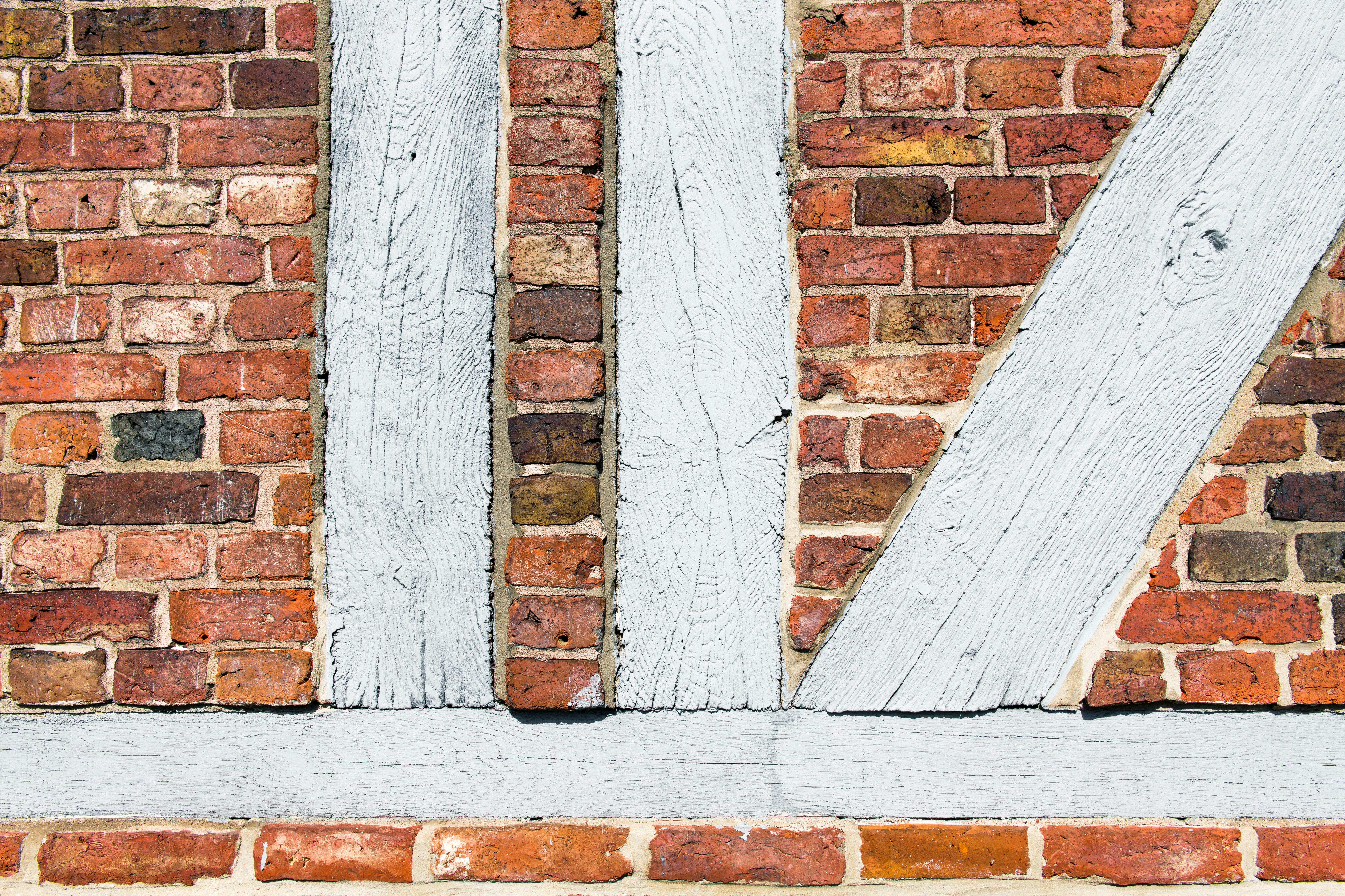 무료 독일 게스타흐트의 목조 프레임 붉은 벽돌 벽을 클로즈업으로 찍은 사진으로, 오래된 건축물을 보여줍니다. 스톡 사진