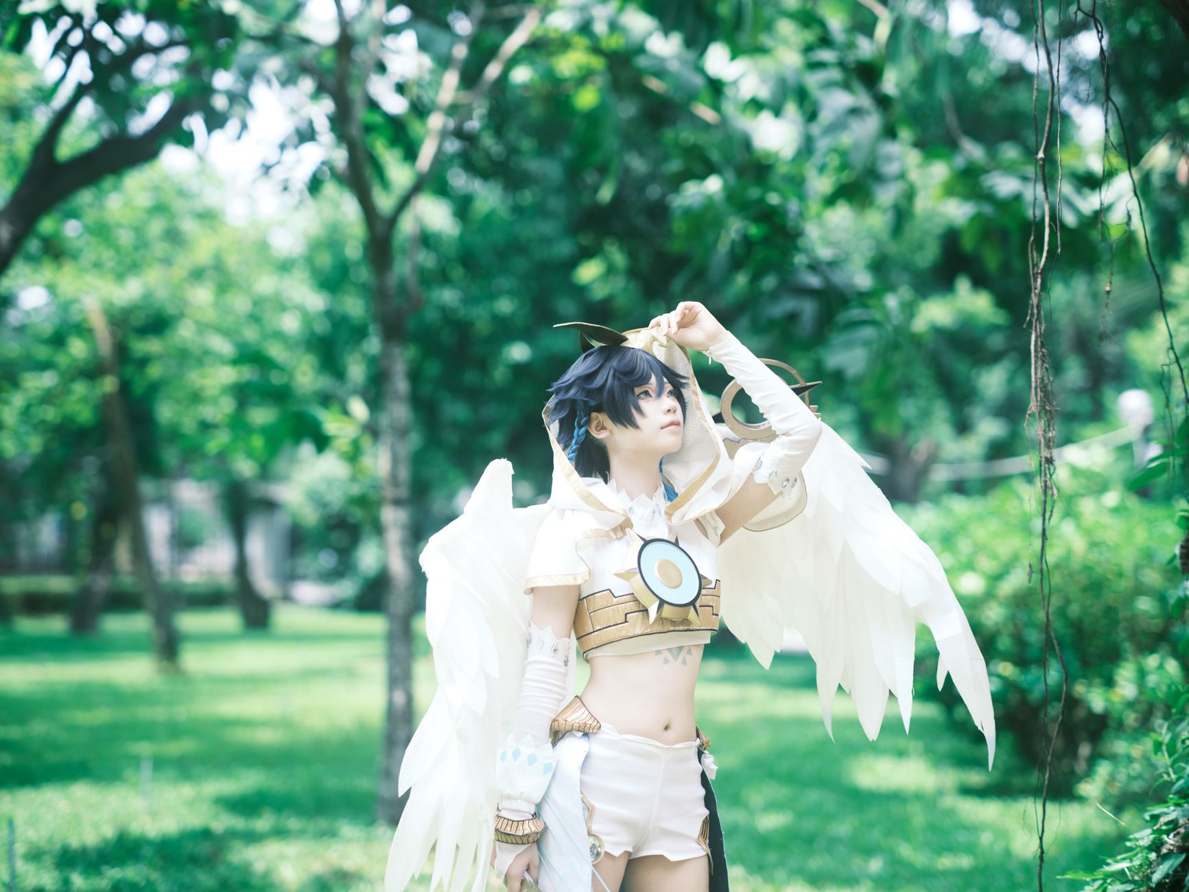 Cosplayer with wings in a vibrant green park environment.