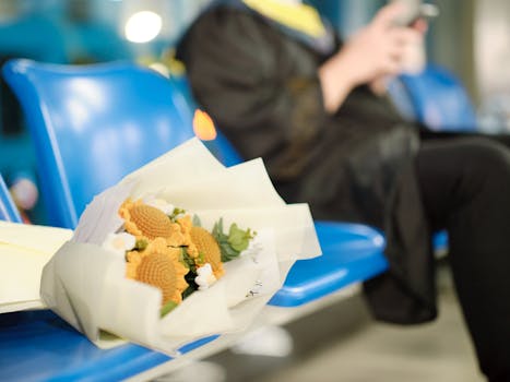 Bouquet of yellow flowers on a chair with a graduate blurred in the background, indoors.