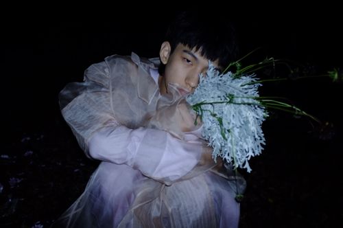 Free A creative nighttime portrait of a fashionable person holding a unique flower arrangement. Stock Photo