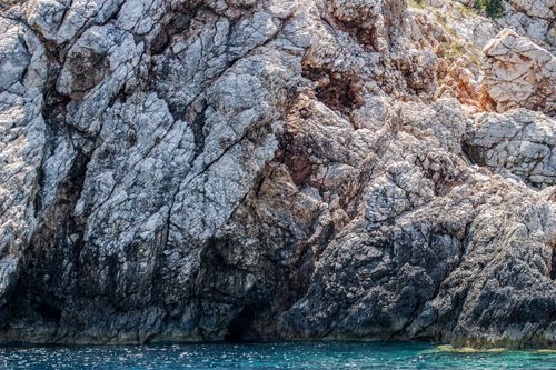 Free Dramatic rocky cliffs rising above the clear blue sea, capturing nature's raw beauty. Stock Photo