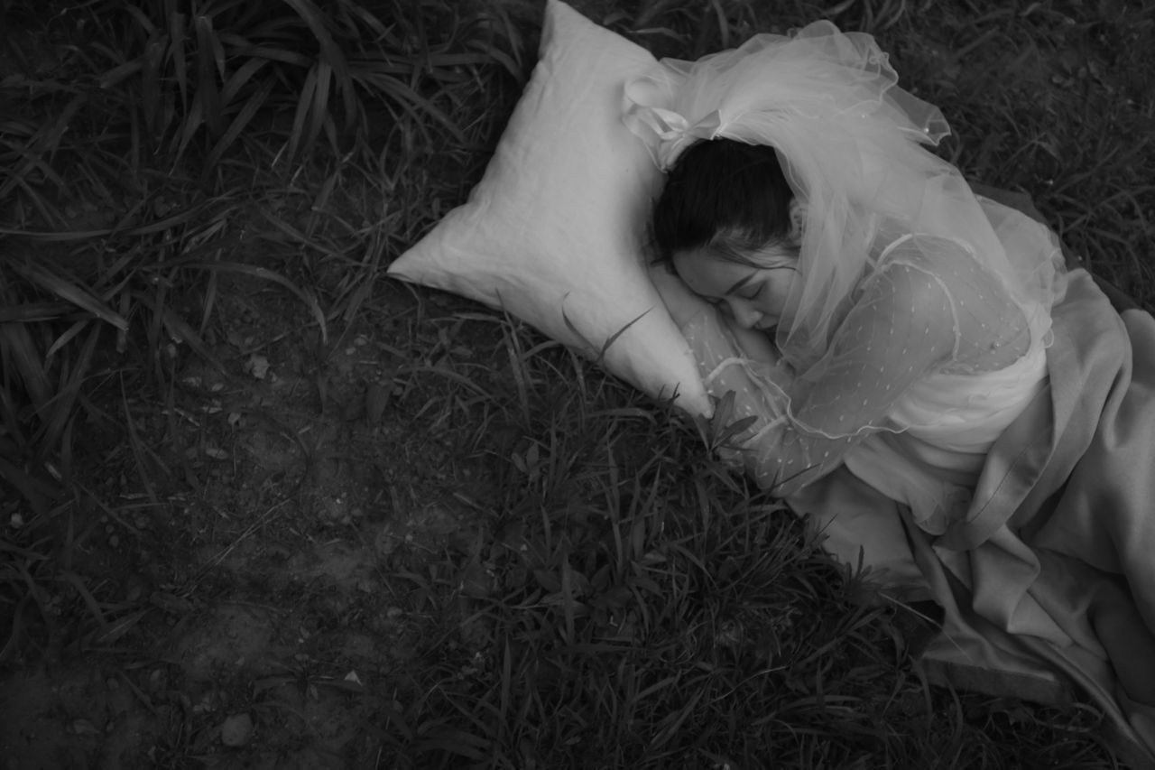 black and white photo of a woman sleeping outdoors in grass capturing