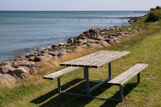 Wooden picnic table by a rocky shore in Denmark, overlooking the North Sea.