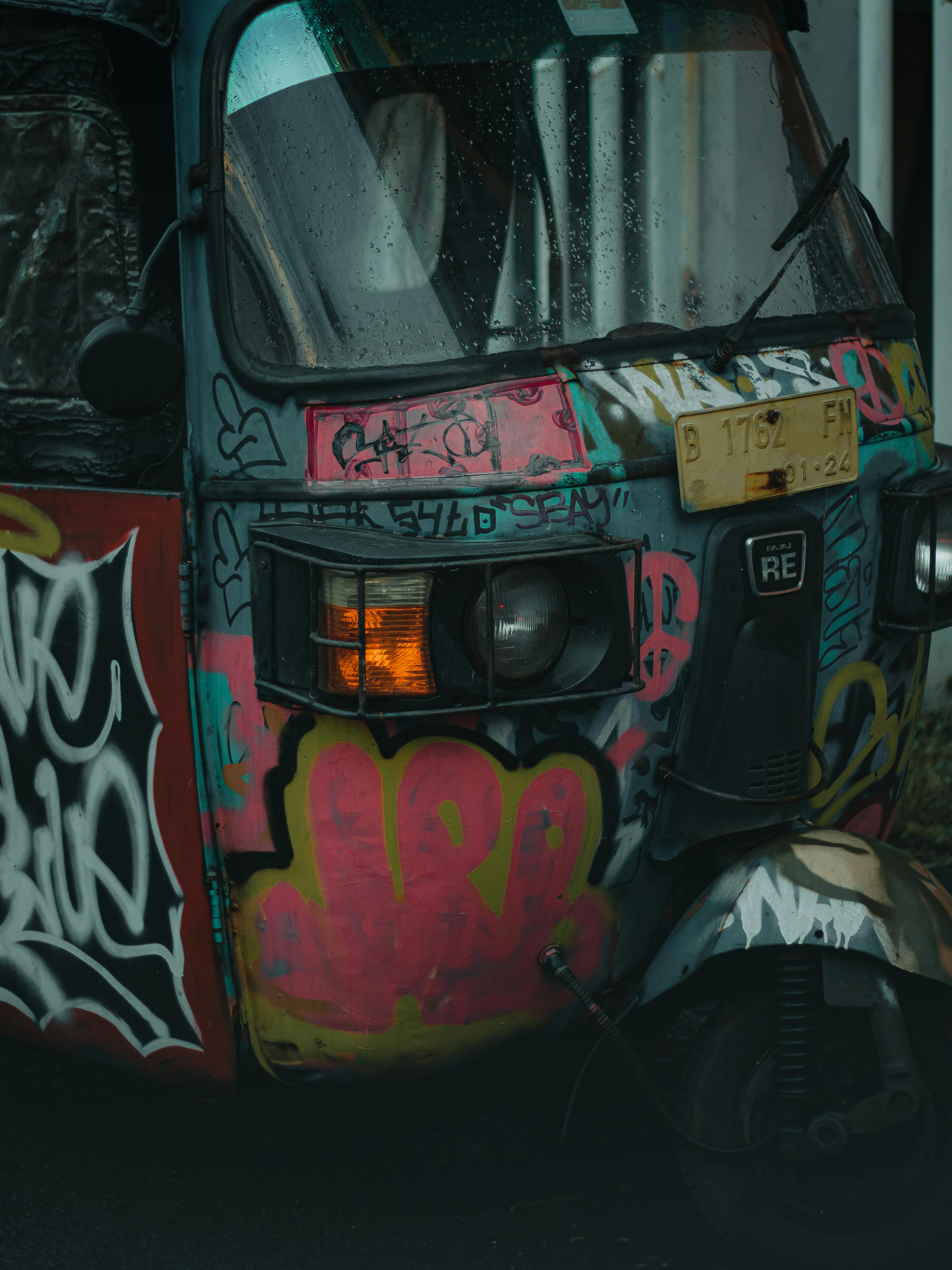 De franc Un rickshaw vibrant a Jakarta, cobert de grafits de colors en un dia plujós. Foto d'estoc