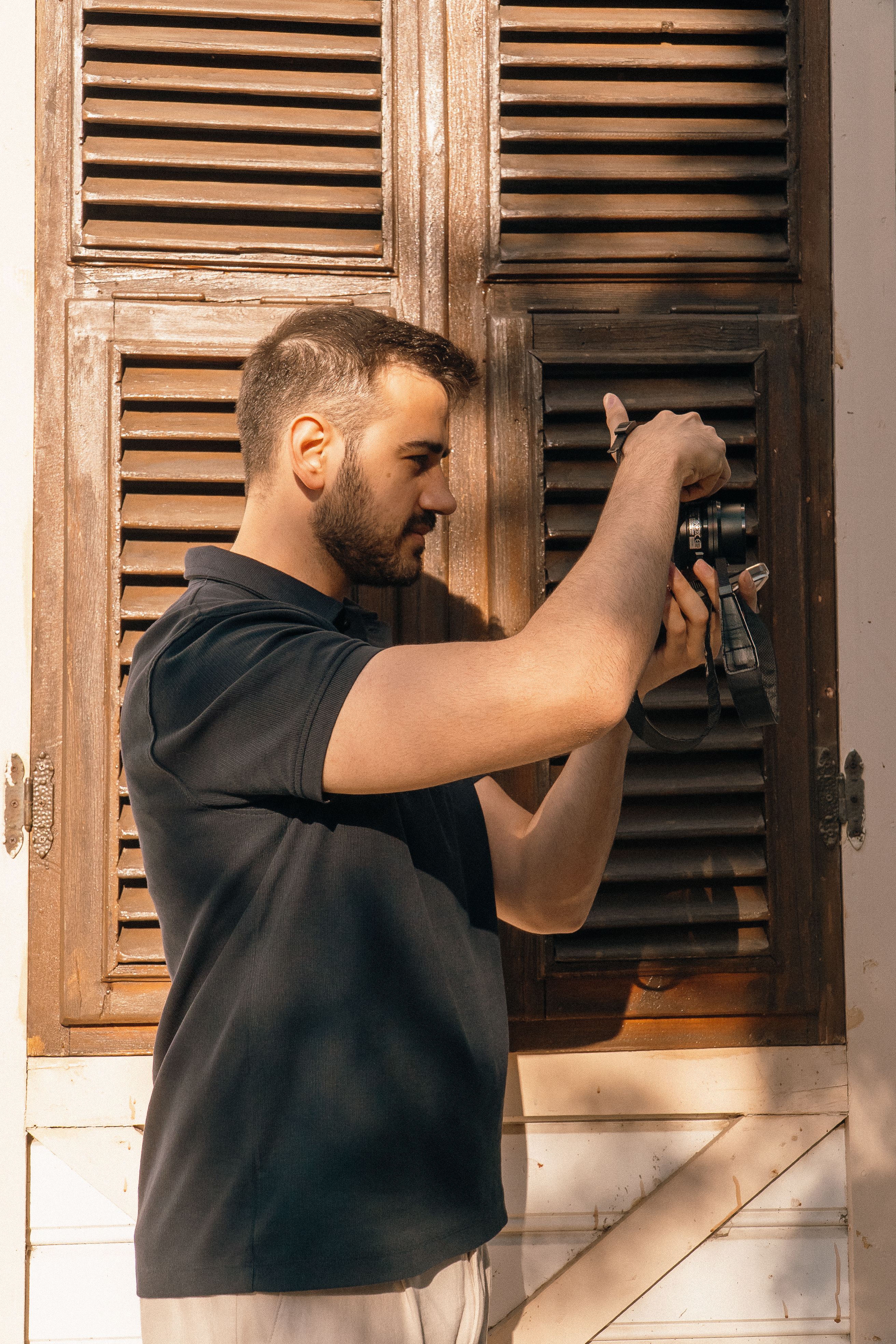 Adult man taking a photograph outdoors in summer sunlight, emphasizing creative focus.