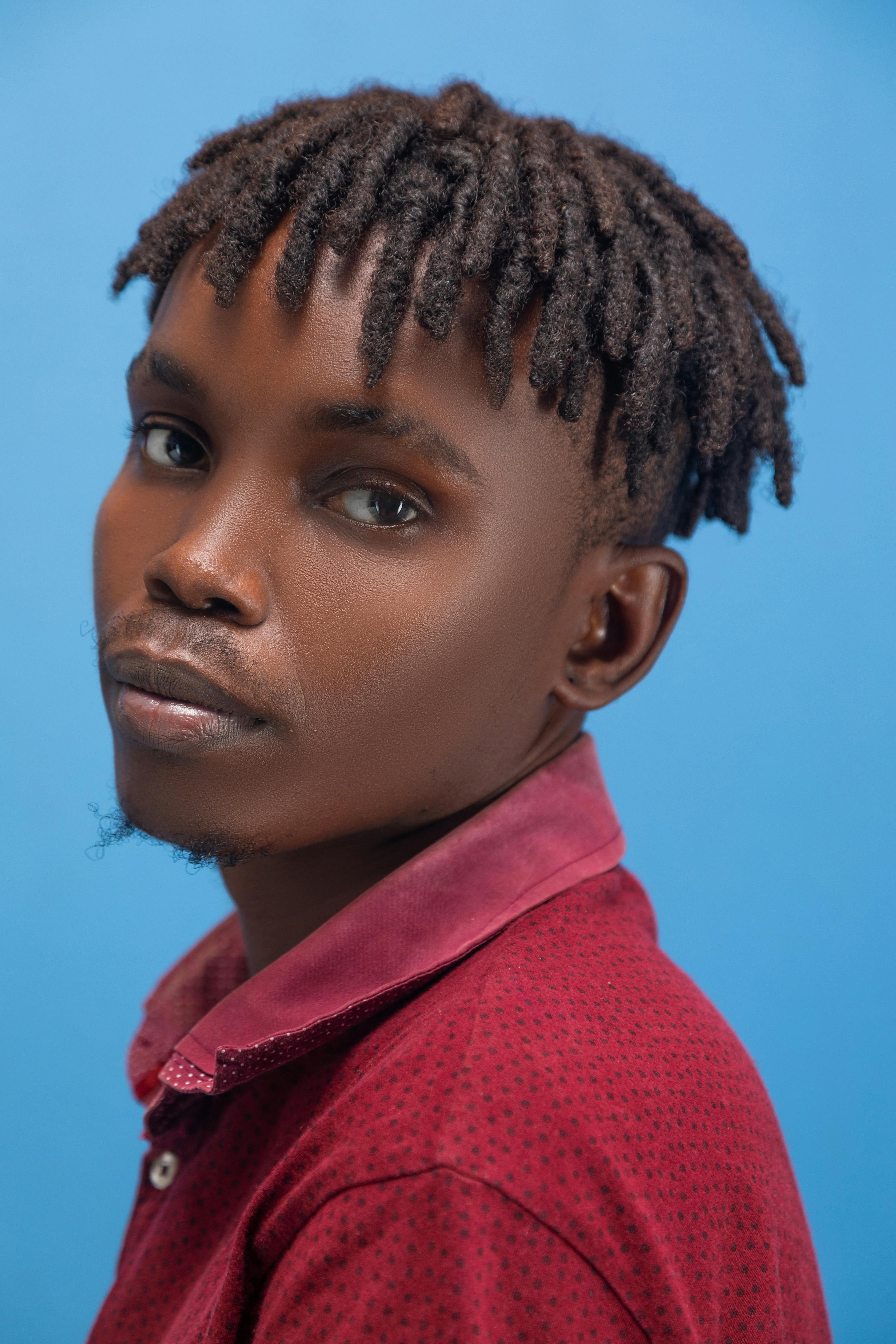 Bezpłatne Portret młodego mężczyzny z dredami na niebieskim tle, emanującego pewnością siebie. Zdjęcie z galerii