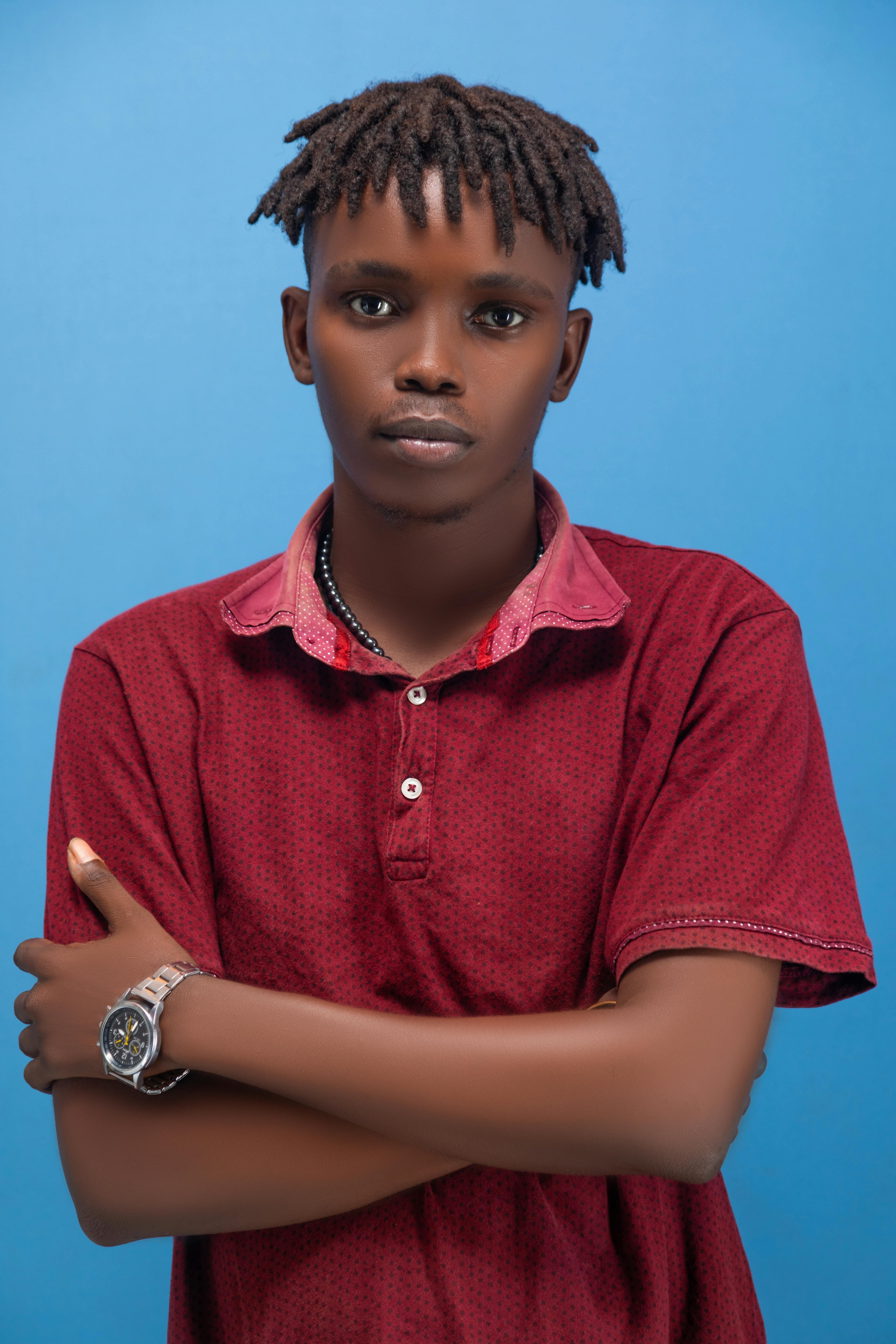 Bezpłatne Portret młodego mężczyzny w czerwonej koszuli, pewnie pozuje na niebieskim tle. Zdjęcie z galerii