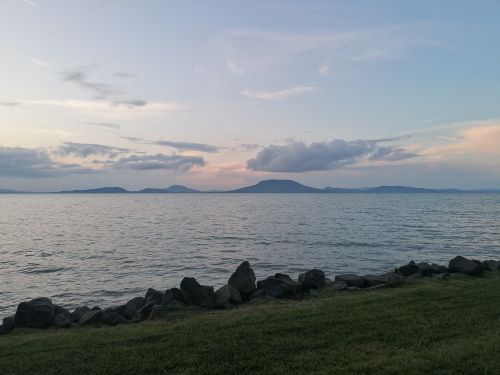 Free Peaceful sunset view at Balatonfenyves, Hungary with clouds over distant hills and calm waters. Stock Photo