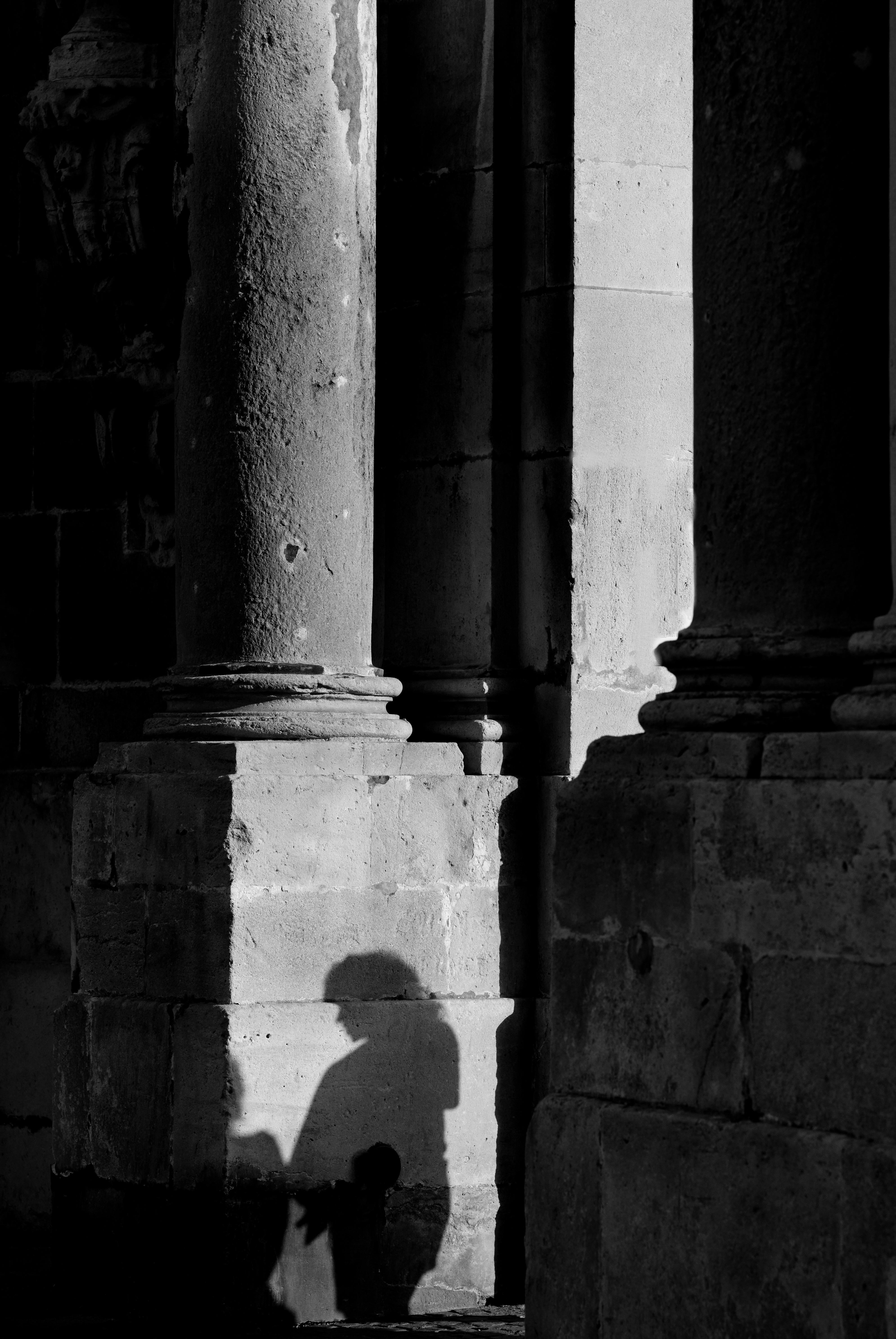 Dramatic black and white shadow of a person on ancient stone columns in Nancy, France.
