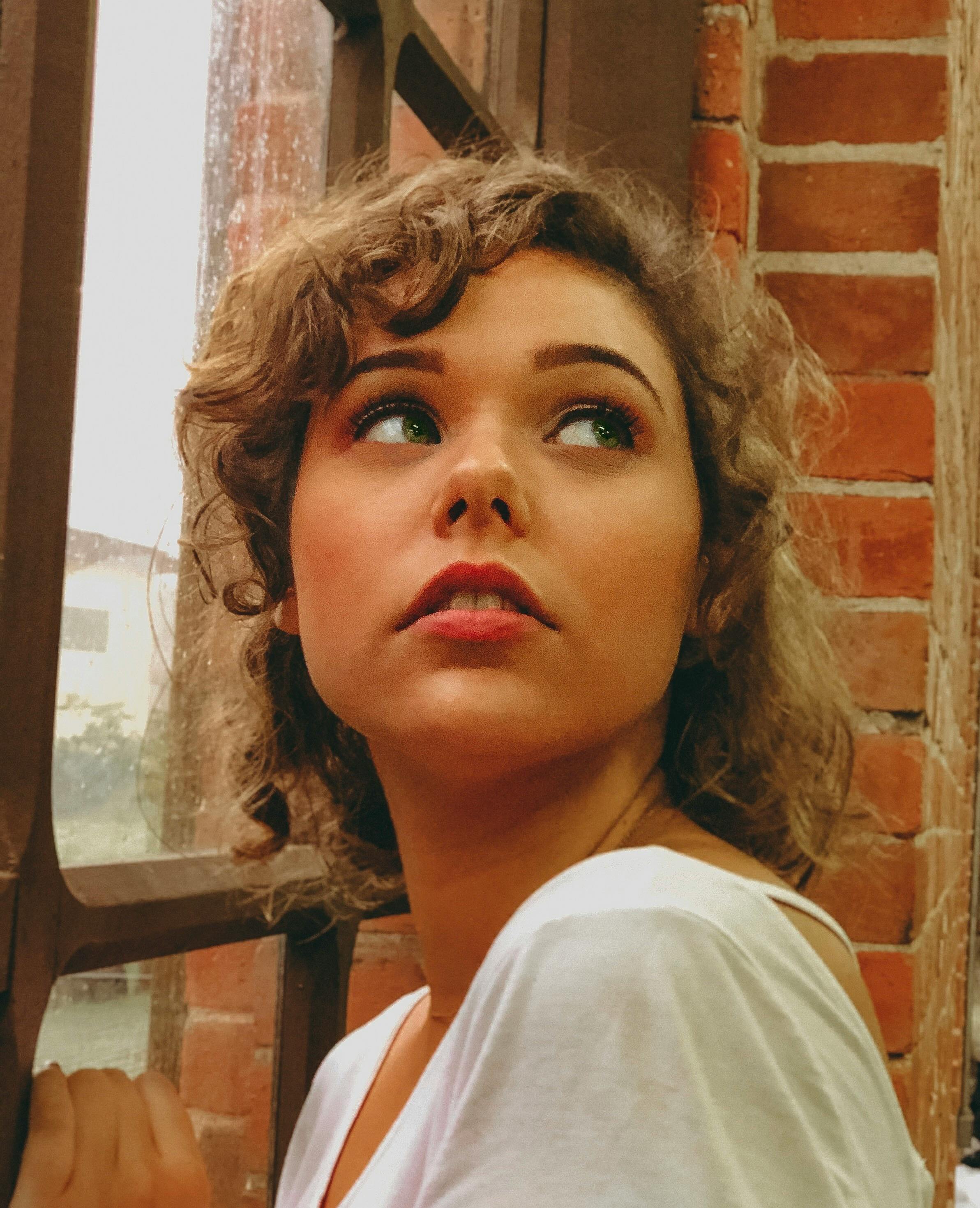 Caucasian woman looks contemplatively out of a window in Paranapiacaba, Brazil.