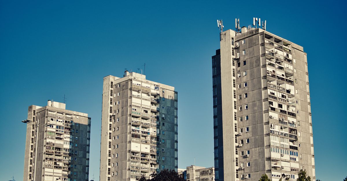 Row of tall urban apartment buildings against a clear blue sky, showcasing modern architecture.