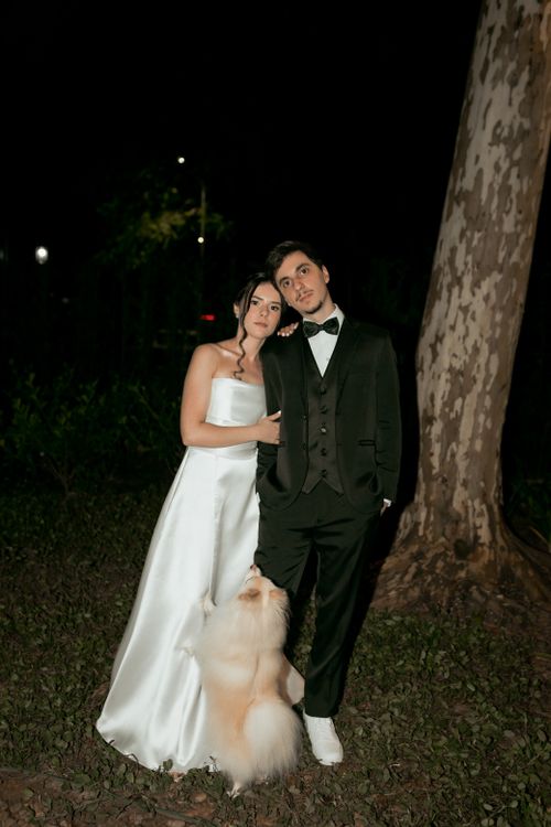 Free Bride and groom posing with dog at nighttime wedding outdoors. Stock Photo