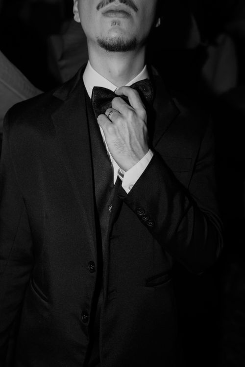 Free Close-up of a man adjusting a bow tie, showcasing elegance in black and white tones. Stock Photo