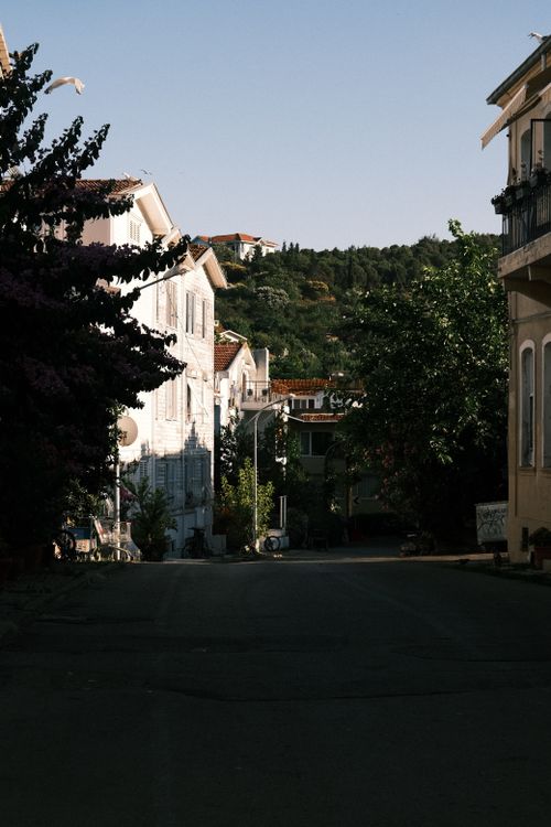 Free Sunlit streets of a quaint town with scenic architecture and lush greenery. Stock Photo