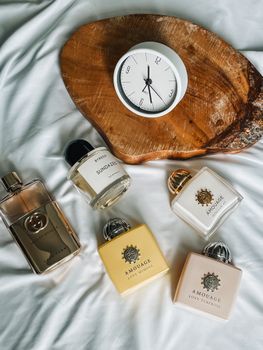 Stylish flat lay of luxury perfumes and clock on wood slab for chic lifestyle inspiration.