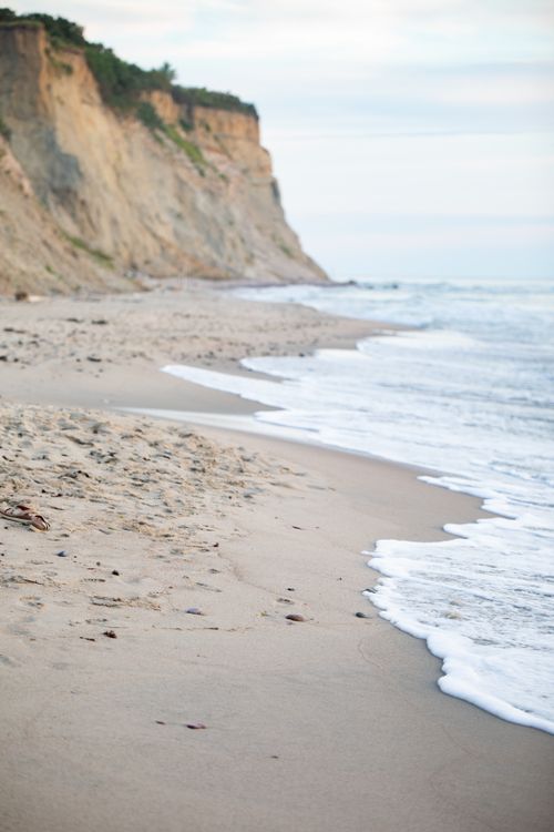 Free Serene coastal landscape with cliffs and gentle waves on a sandy beach. Stock Photo