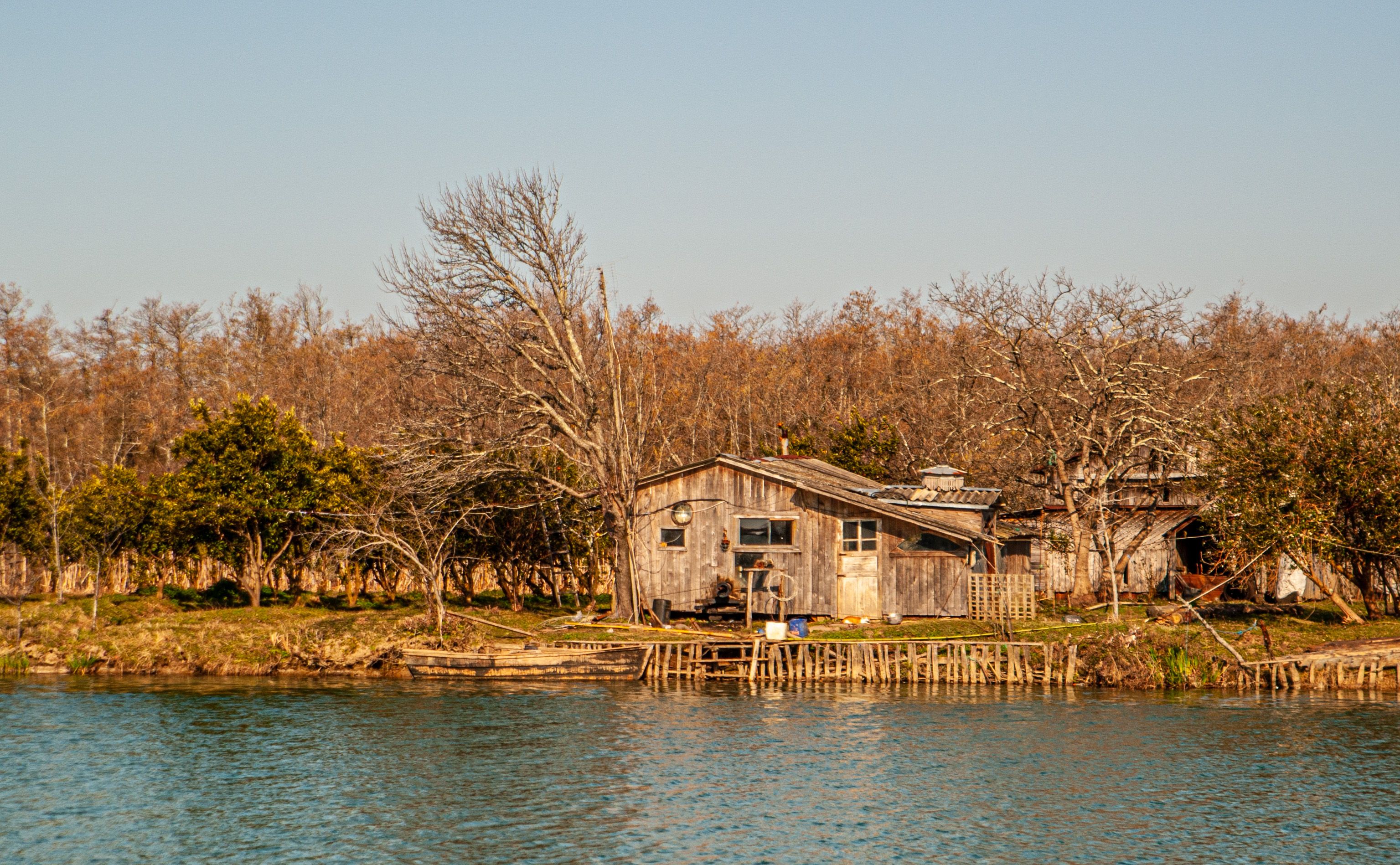 A serene view of a rustic cabin by a lake surrounded by autumn trees.