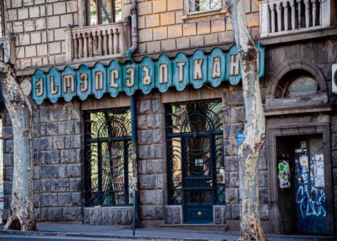 Elegant stone building facade with vintage style lettering and ironwork details, showcasing urban architecture.