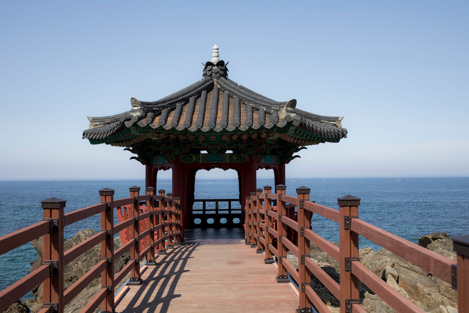 A serene traditional Korean pavilion with ocean views captured on a sunny day.