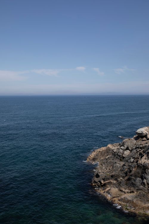Free Dramatic rocky coastline with expansive ocean under a bright clear sky. Stock Photo