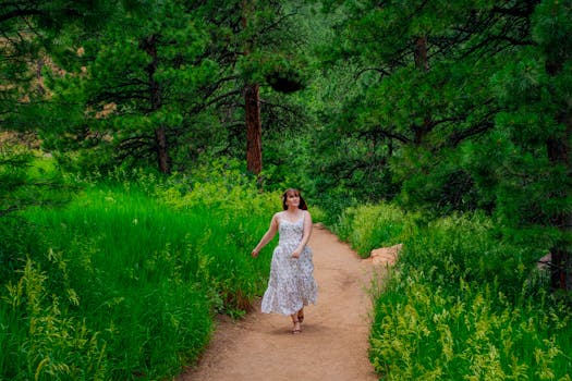 A young woman in a summer dress walking along a forest trail in Boulder, Colorado, on a sunny day.