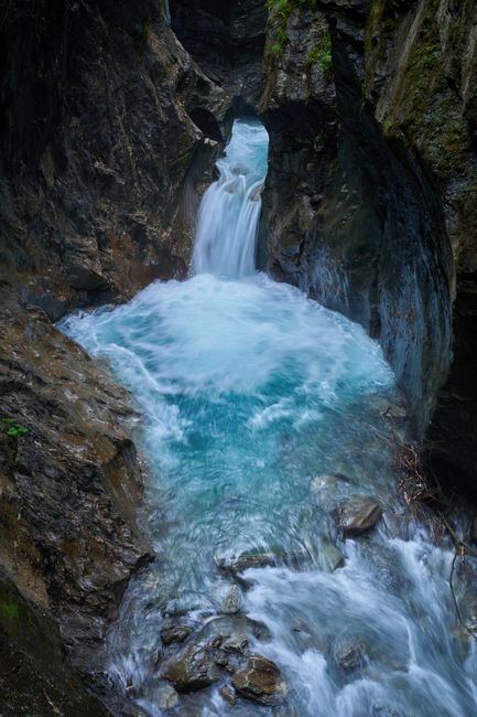 Captivating waterfall inside Kaprun Gorge, Austria, showcasing vibrant turquoise waters and rugged rocky cliffs.