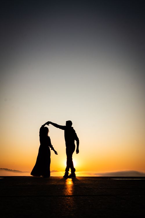 Free Silhouette of a couple dancing on a beach at sunset, creating a romantic and serene scene. Stock Photo