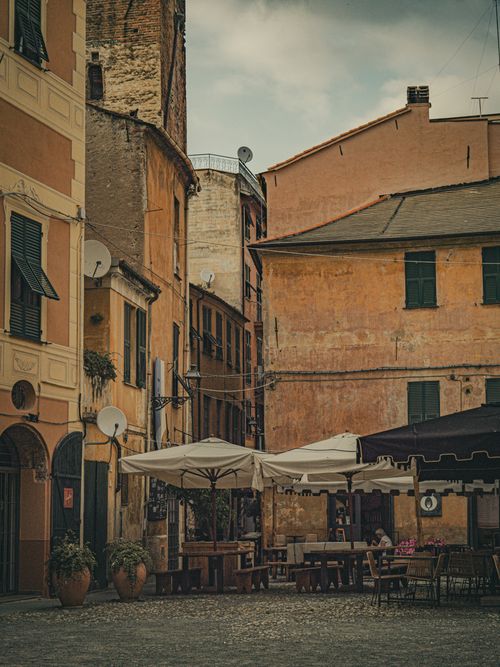 Free Quaint outdoor cafe in a historic European square with rustic buildings and cozy seating. Stock Photo