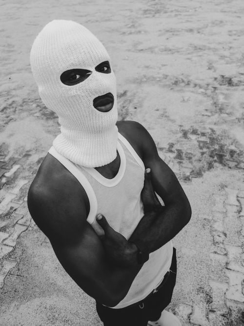 Free Dramatic portrait of person in ski mask with arms crossed, captured in moody black and white. Stock Photo