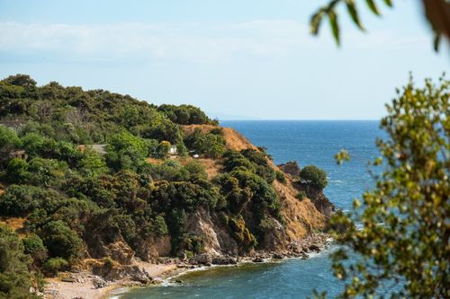 Free A scenic view of a lush green cliffside by the sparkling blue ocean on a sunny day. Stock Photo