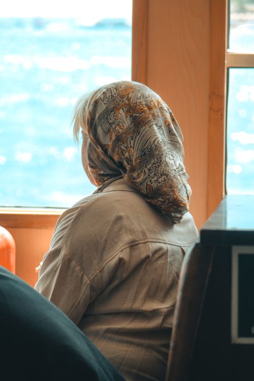 Free Woman with headscarf looking out the window, capturing serene and contemplative moment. Stock Photo