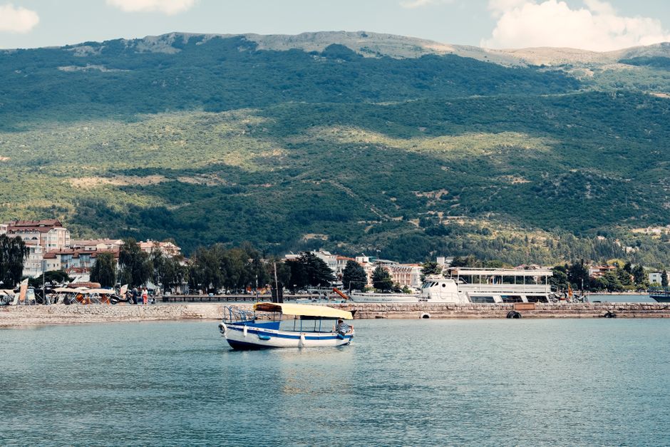 Peaceful scene of a boat on Lake Ohrid with a mountainous backdrop in North Macedonia.