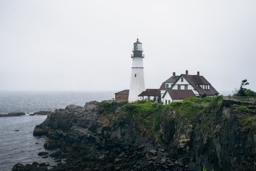 Free Scenic view of Portland Head Lighthouse with rocky coastline under overcast skies. Stock Photo