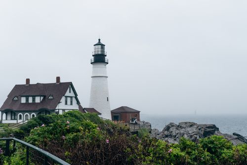 Free Iconic Portland Head Light lighthouse standing tall amidst foggy coastal landscape, Maine. Stock Photo