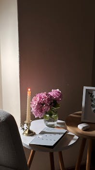 A serene indoor setting with pink hydrangeas, lit candle, and modern decor creating a cozy atmosphere.