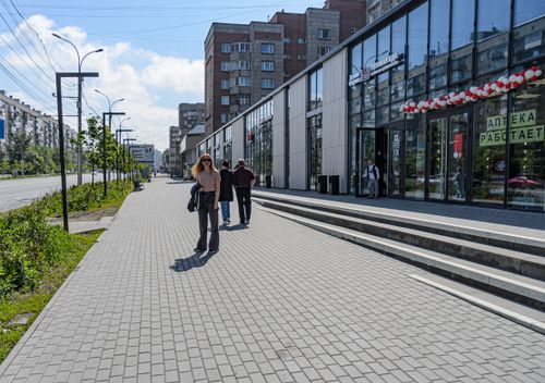 Free Pedestrians walking outside a modern shopping center on a sunny day, showing urban lifestyle. Stock Photo