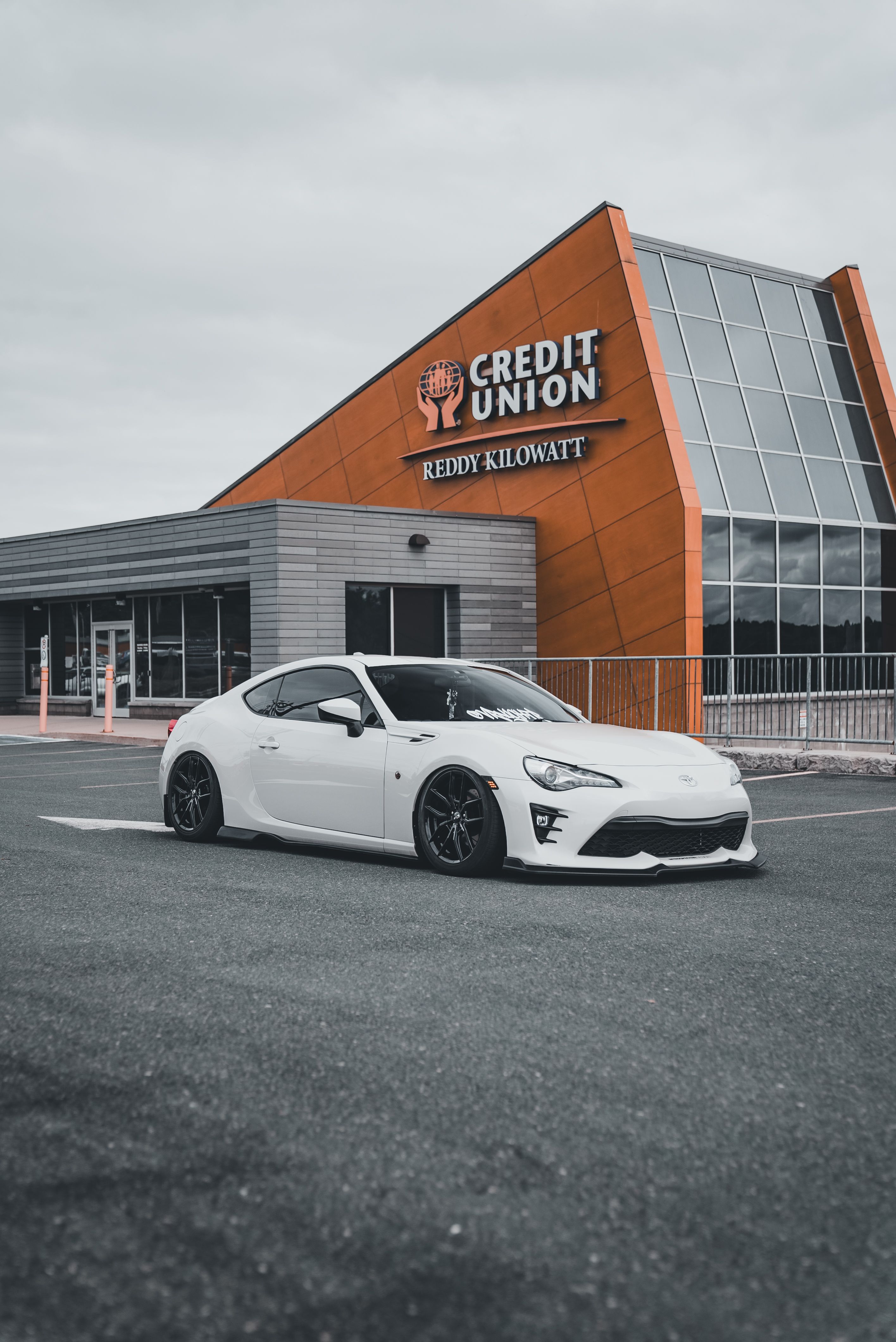 Sleek white sports car in front of Credit Union with modern architecture.