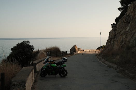 A serene coastal road at dusk with a parked motorcycle and a sea view, perfect for travel inspiration.