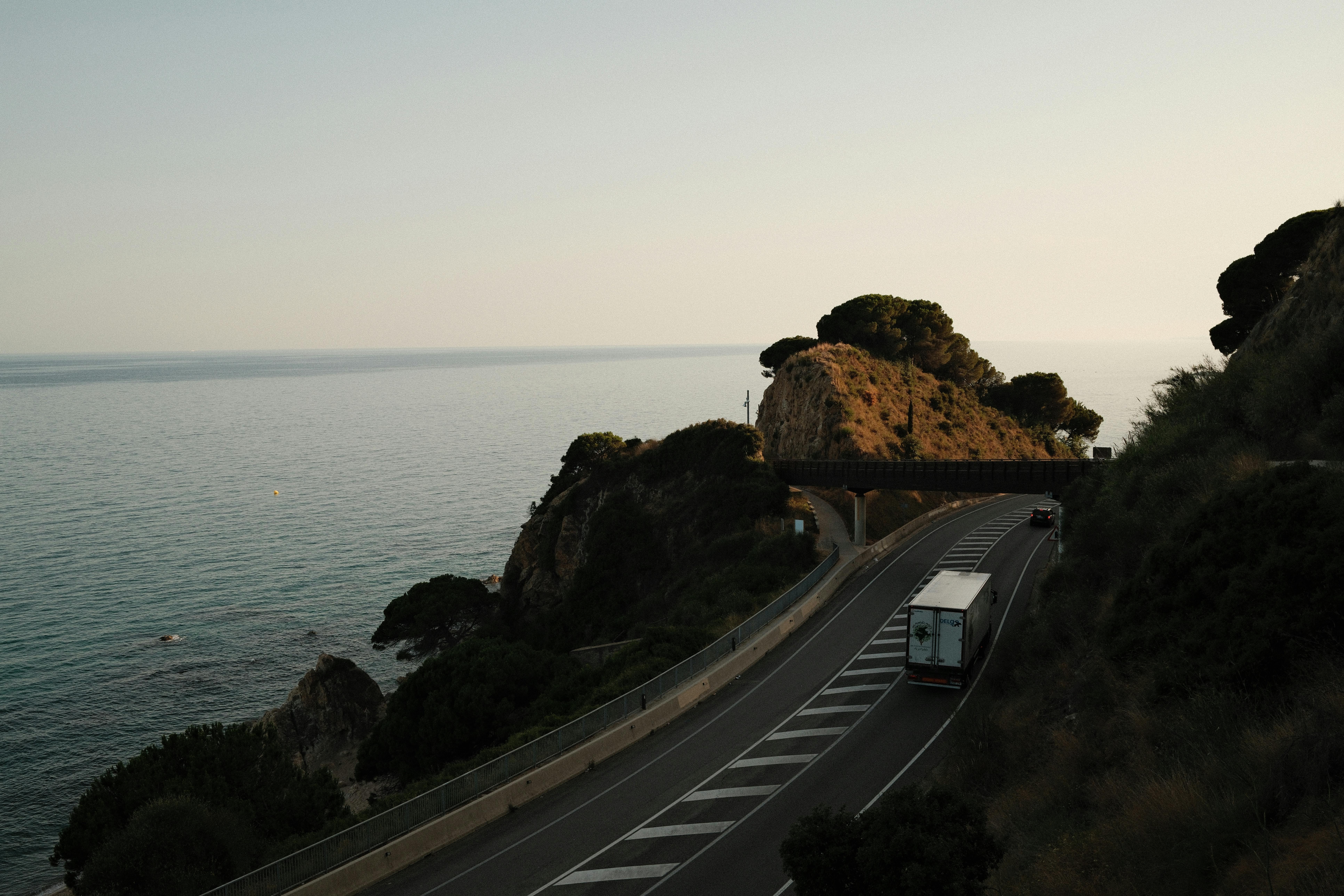Truck on a coastal road with a stunning ocean view at sunset, capturing serene travel vibes.