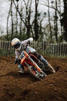 Motocross rider takes a sharp turn on a dirt track in Mothern, France. High-energy sports action.