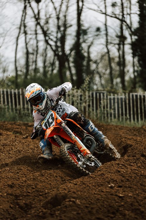 Free Motocross rider takes a sharp turn on a dirt track in Mothern, France. High-energy sports action. Stock Photo