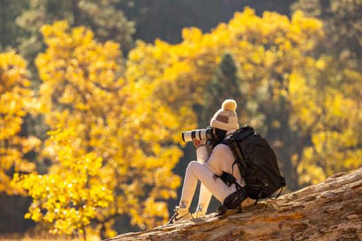 A woman taking photographs amidst stunning autumn foliage in a forest setting.