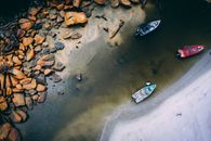 空中拍摄令人惊叹：船只靠近岩石海岸线，海水清澈