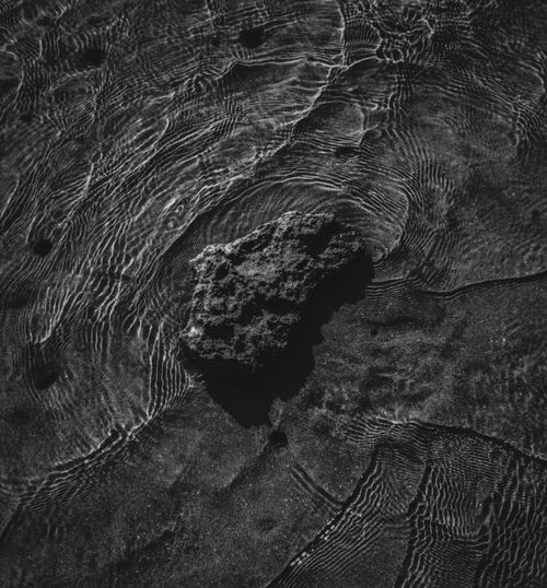 Free A rock in rippled water creating a captivating black and white texture effect. Stock Photo