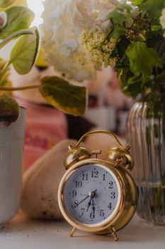 Gold alarm clock with flowers in a cozy, vintage setting.